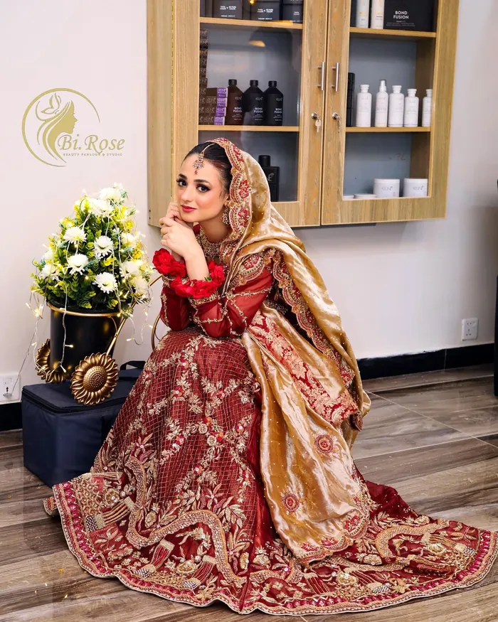 Bride in a gold-embroidered outfit, seated in the Bi Rose studio